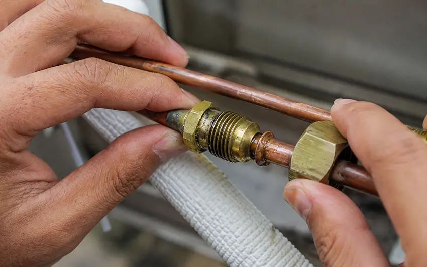 Thợ kỹ thuật đang kiểm tra khớp nối rắc co ống đồng – vị trí rất dễ bị hở đầu loe hoặc siết lỏng gây rò rỉ gas máy lạnh.